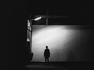 silhouette of man standing under lamp post